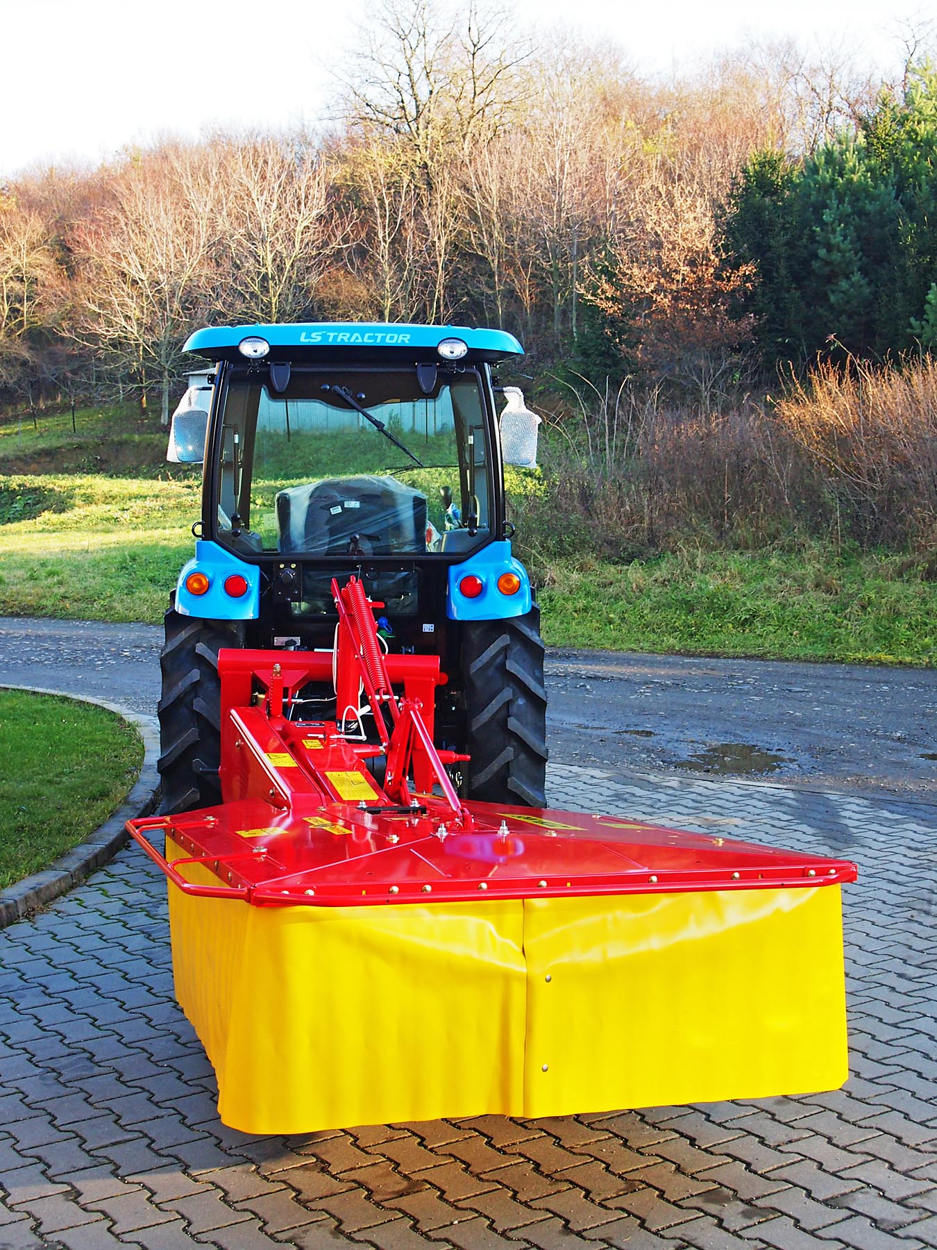 Traktor LS XR50 s dvoububnovou rotační sekačkou v přepravní poloze.