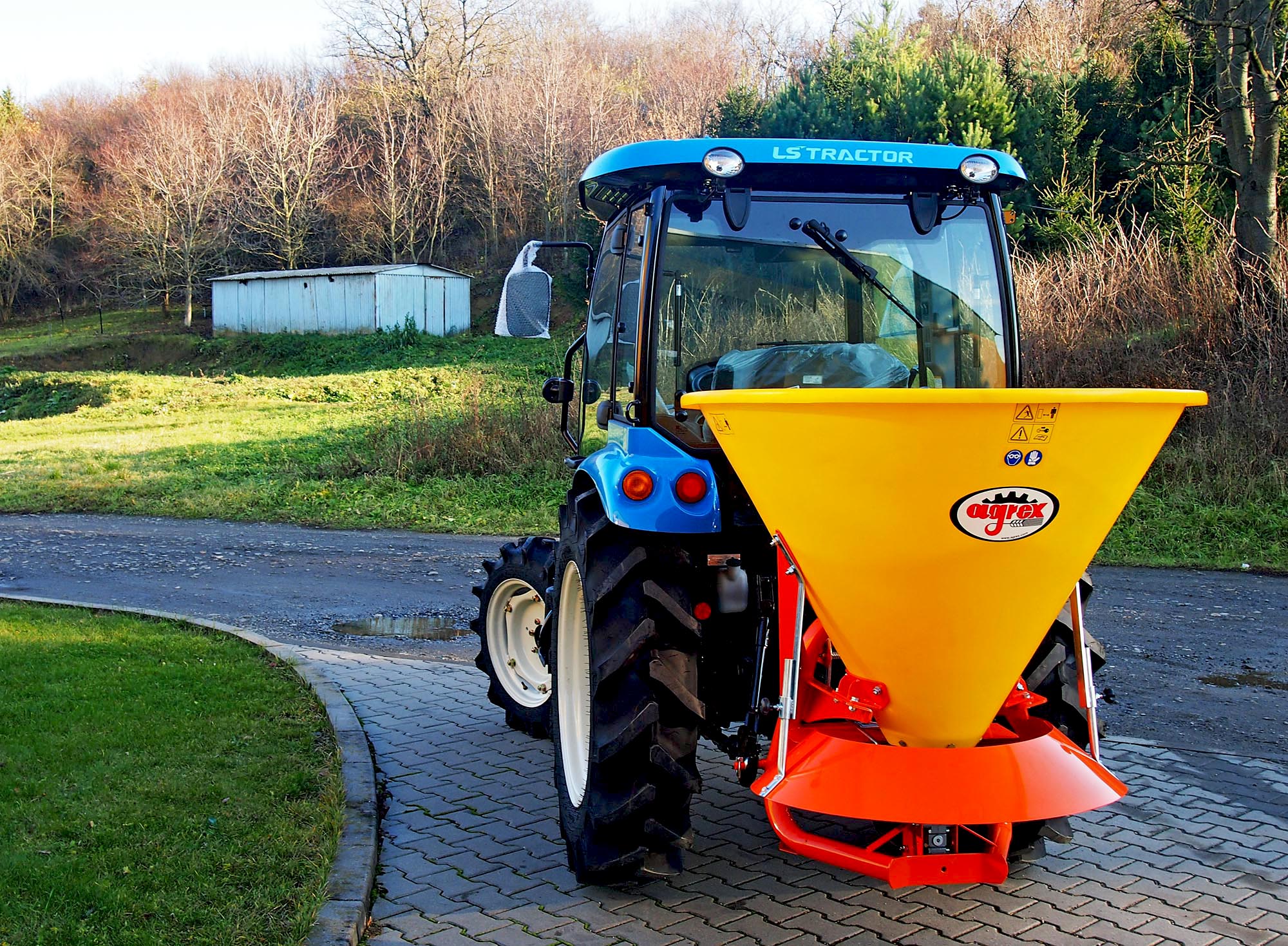Komunální traktor LS XR50 s rozmetadlem sypkých hmot.